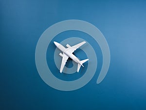 White plane toy model at the center on blue background, top view, minimal style. White airplane, flat lay design.