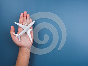 White plane toy model on hand on a blue background with copy space, top view, minimal style