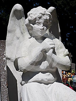 White plaster angel as guardian of the grave in the cemetery