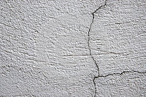 White plaster painted wall with cracks. Cracked wall closeup photo. Architecture detail background