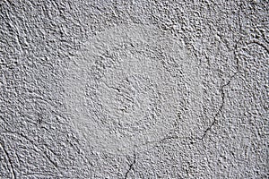 White plaster painted wall with grit and cracks. Cracked wall closeup photo. Architecture detail background