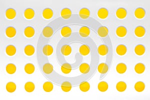 White plastic background with regular holes on yellow background. Copy, empty space for text