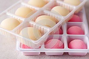 White Plastic Box with Japanese rice desert mochi Colouful mochi cakes Tasty fruit and Vanilla mochi on grey background.