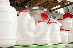 White plastic cans with red lids on a rack stillage