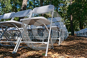 White plastic chairs set up an outdoor in a row before ceremony, event or party