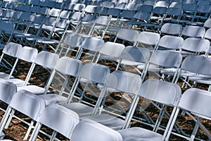 White plastic chairs set up an outdoor in a row before ceremony, event or party