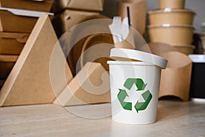 A white plastic container or glass with a green recycle symbol on the background of ecological utensils.