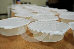 White plastic deep disposable plates stand on a wooden table. zero weist, recycling, global warming