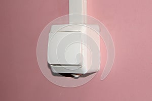 White plastic electrical switch on a pink wall