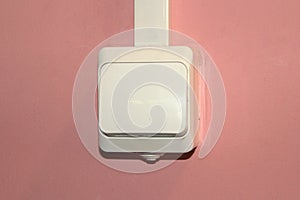 White plastic electrical switch on a pink wall