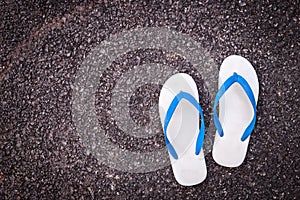 White plastic flip flop shoe on black asphalt road