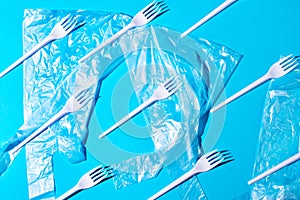 White plastic forks and bags on blue background.