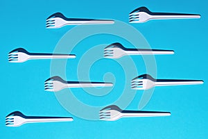 White plastic forks on blue background