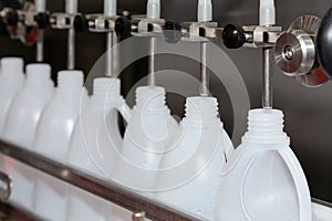 White plastic gallons or bottle on the production line of the conveyor at filling machine in the factory. selective focus.