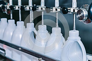 White plastic gallons or bottle on the production line of the conveyor at filling machine in the factory. selective focus.