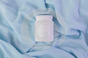 White plastic jar with vitamins and bioactive additives. Useful pills for youthful skin on a beautiful blue background with copy photo