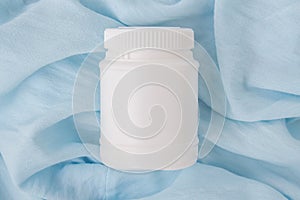 White plastic jar with vitamins and bioactive additives. Useful pills for youthful skin on a beautiful blue background with copy photo