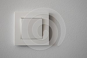 White plastic light switch on light gray wall, close-up