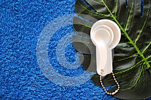 White plastic measuring spoons lie on a palm leaf on a blue cloth background