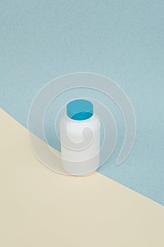 White plastic medical container for tablets or capsules on a yellow-blue background