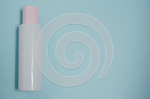 White plastic mock-up of a bottle of cosmetic lotion  peeling  cream with a pink cap on a blue background. Top view with a copy of