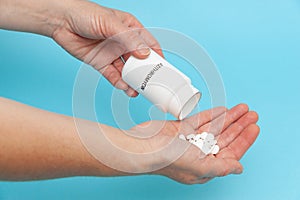 White plastic packaging bottle in the hands with tablets