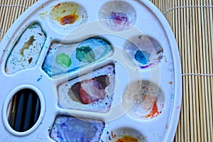 White plastic palette with paints on a wooden table