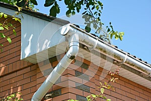 White plastic rain gutter. House roof guttering repair.