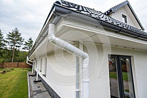 White plastic rain gutter system with drainage pipe