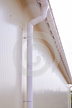 White plastic rain guttering system. Guttering drainage pipe exterior.