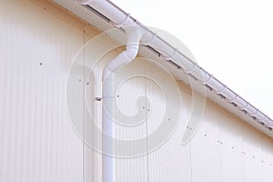 White plastic rain guttering system. Guttering drainage pipe exterior.