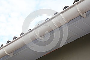 White plastic roof gutter pipeline with holders.