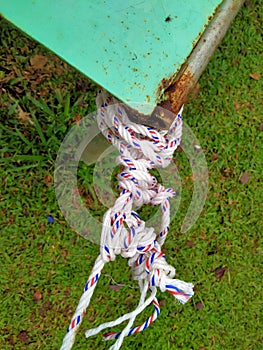 White plastic rope tied and knotted at the end of the green iron table pole.