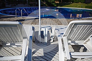 White plastic sun beds by the pool.