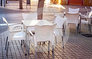 white plastic table surrounded by chairs on the terrace of a small cafe