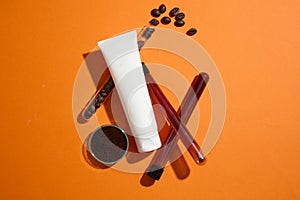 A white plastic tube displayed on orange background with test tubes filled of coffee beans and coffee grounds. Top view, mockup
