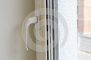White plastic window or door detail with metal handle and transparent glass on light wall copy space background. Installation and