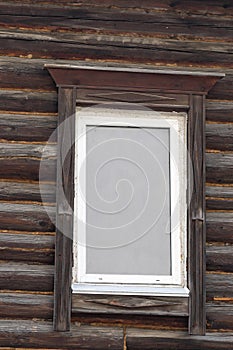 White plastic window with wooden platbands on a log cabin. Meto for photo caption