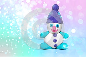 White plasticine snowman with purple winter hat, pink nose, playdough or modeling compound dough, concept of festive atmosphere of