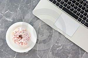 White plate with bagel and laptop keyboard on concrete table