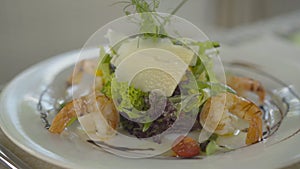 White plate with baked shrimps and vegetables standing on the table in restaurant. Close-up of delicious healthful