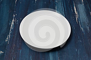 White Plate on blue wooden background side view
