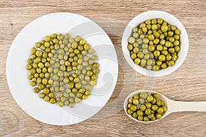 White plate, bowl and wooden spoon with green peas