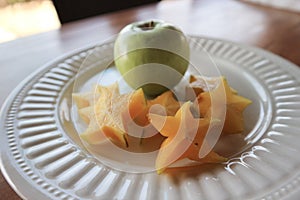 White plate with carambola and fresh apple