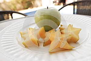 White plate with carambola and fresh apple