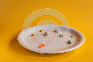 White plate with colored medications on a orange background. Pharmaceutical drug overdose concept
