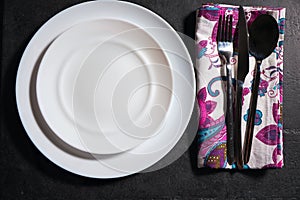 White plate, cutlery and napkin on stone table. Table setting.