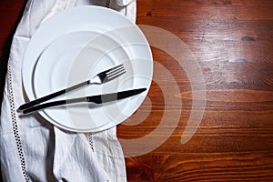 White plate, cutlery and napkin on wooden table. Table setting