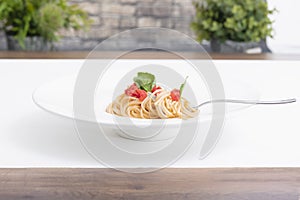 White plate of delicious-looking spaghetti with tomato and basil