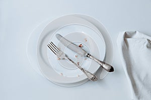White plate with fork, knife and crumpled on a white background